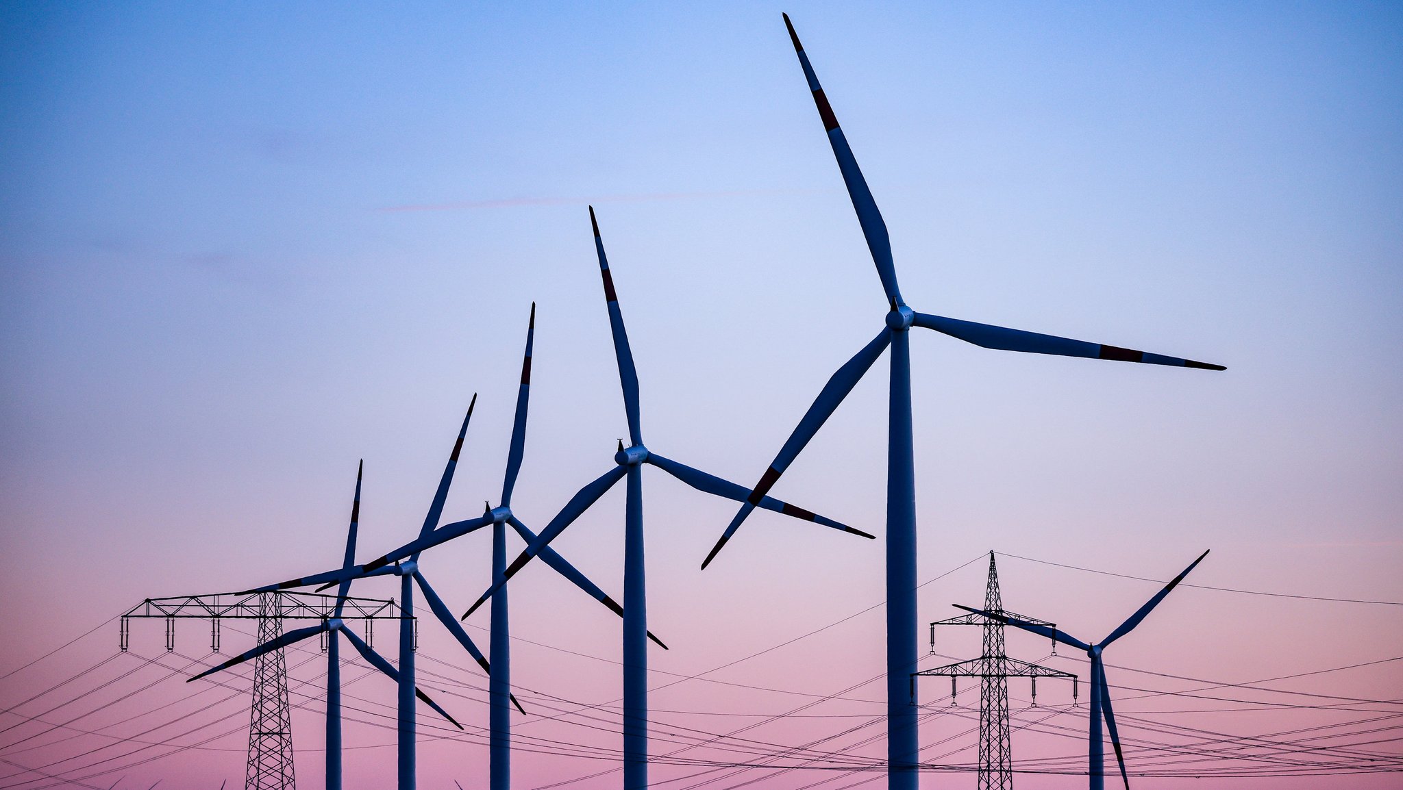 Windkraftanlagen und Hochspannungsleitungen vor dem Abendhimmel (Symbolbild)