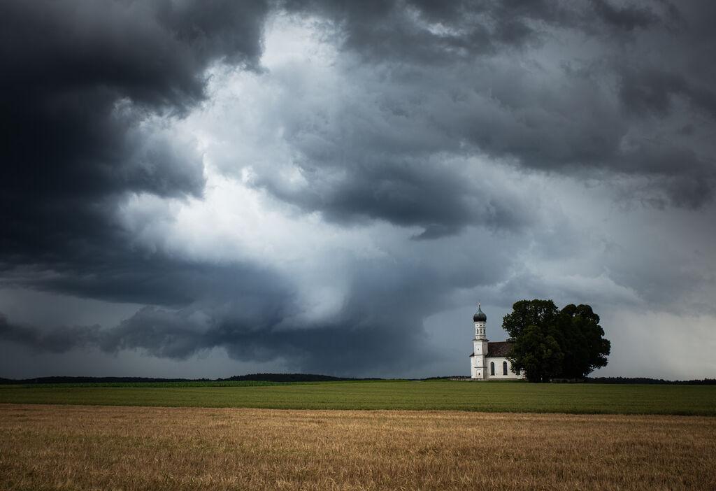 Dunkle Gewitterwolken hinter einer Kirche auf dem Land.