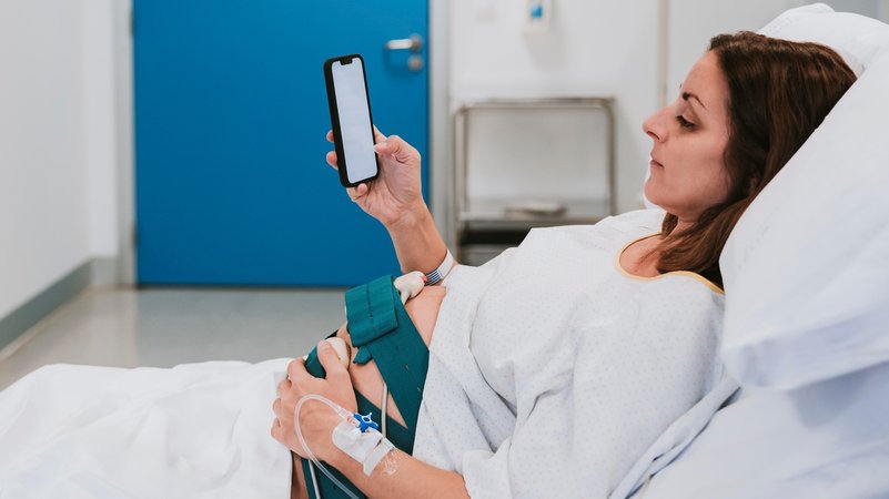 Eine schwangere Frau im Krankenhaus schaut auf ihr Handy. Wird der berechnete Geburtstermin überschritten, wird eine Geburt oft eingeleitet. | Bild: picture alliance / Westend61 | Eva Blanco Eine schwangere Frau im Krankenhaus schaut auf ihr Handy. Wird der berechnete Geburtstermin überschritten, wird eine Geburt oft eingeleitet.
