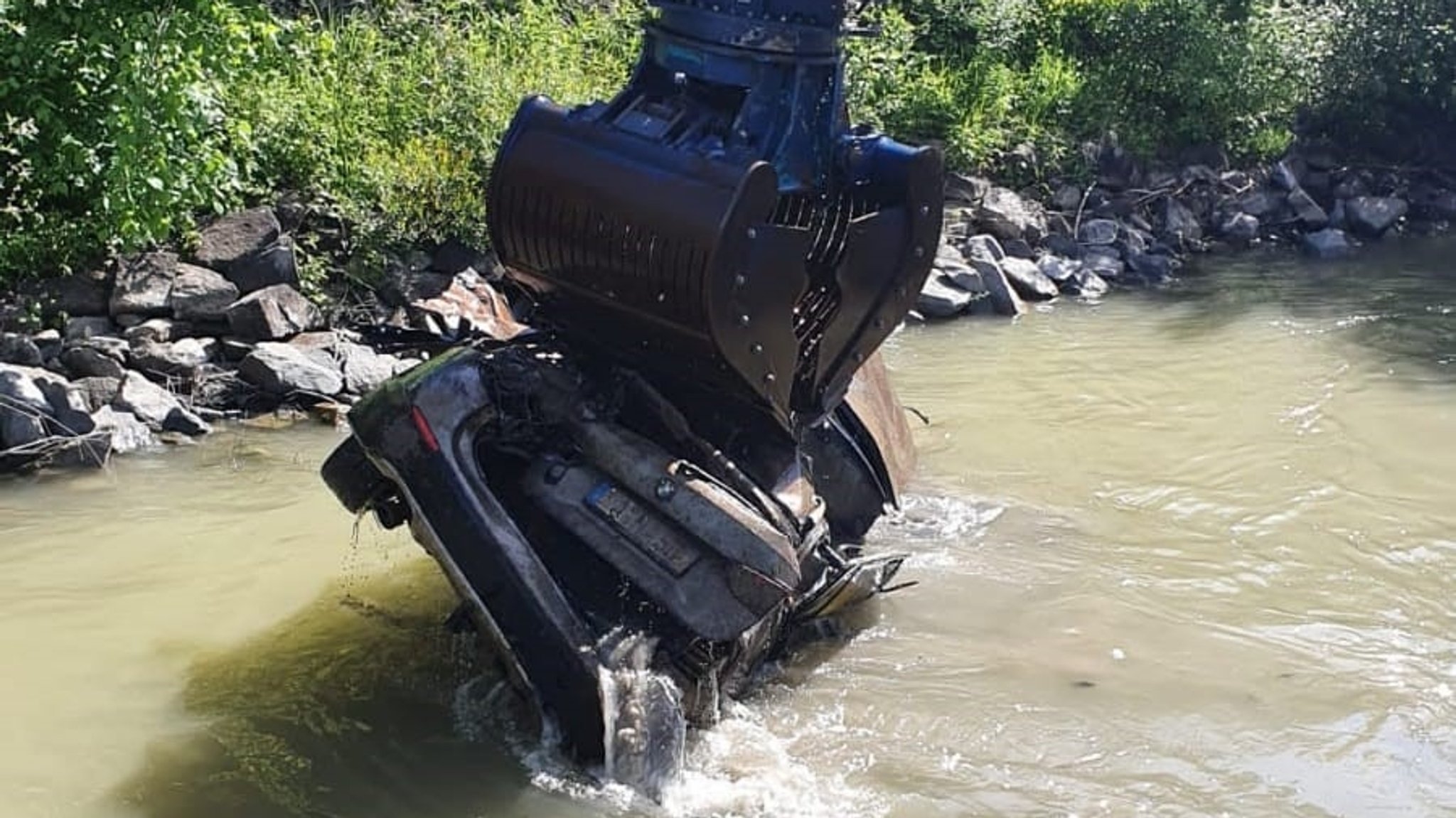 Das Auto wird vom Bagger an Land gehoben