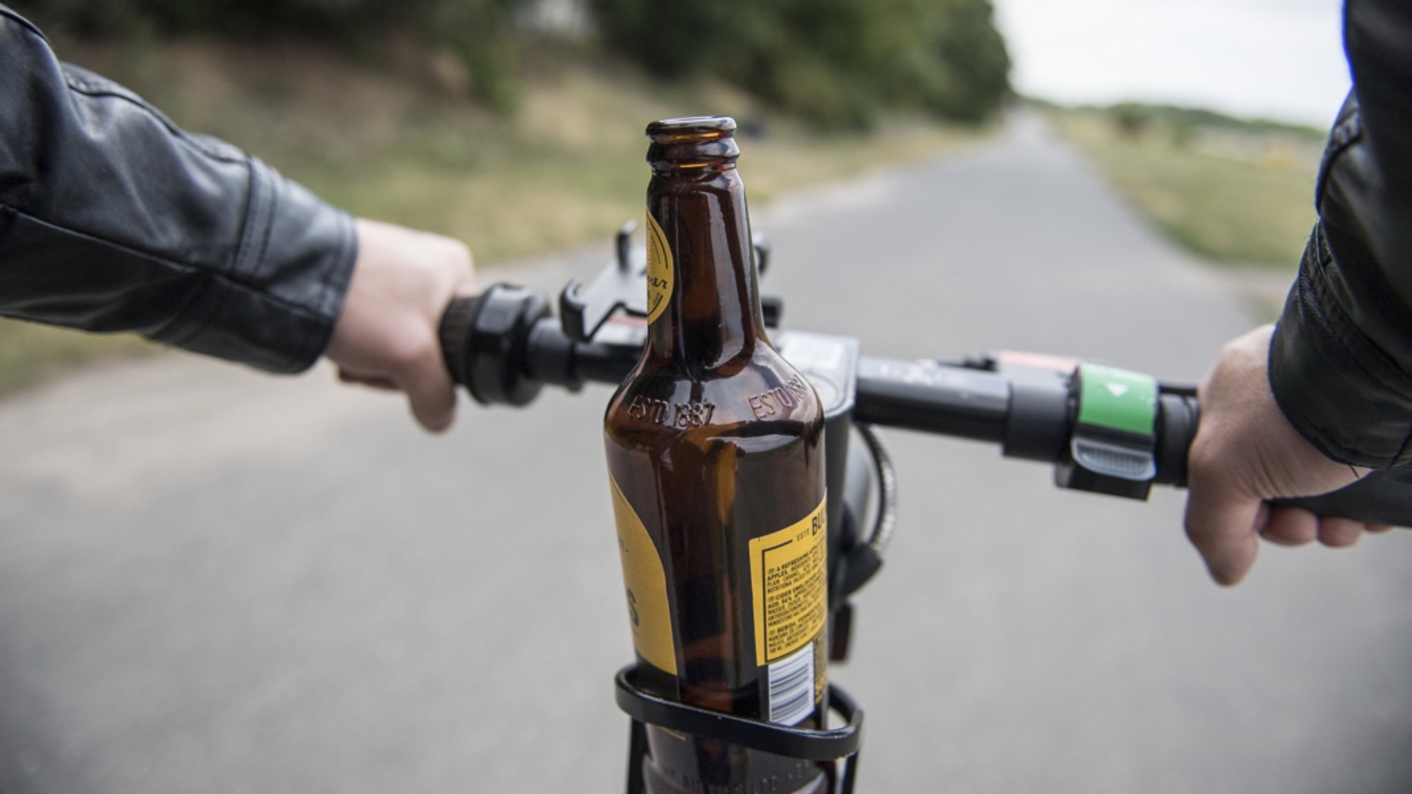 Eine Bierflasche steht in einer Getränkehalterung auf einem E-Scooter. 