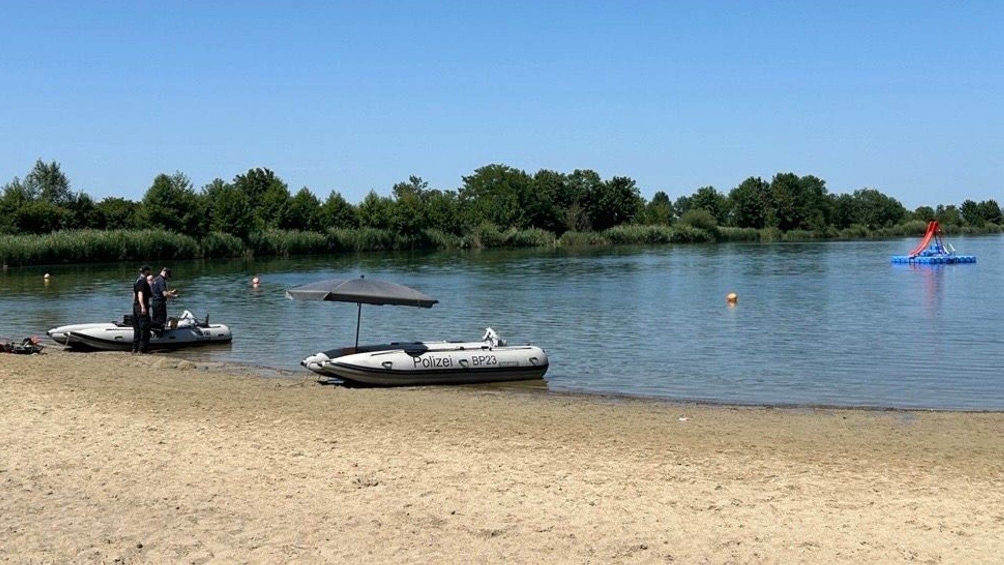 Einsatzkräfte stehen neben Booten der Polizei am Ufer des Mauerner Sees in Neustadt an der Donau. | Bild: BR/Andreas Wenleder Einsatzkräfte stehen neben Booten der Polizei am Ufer des Mauerner Sees in Neustadt an der Donau.