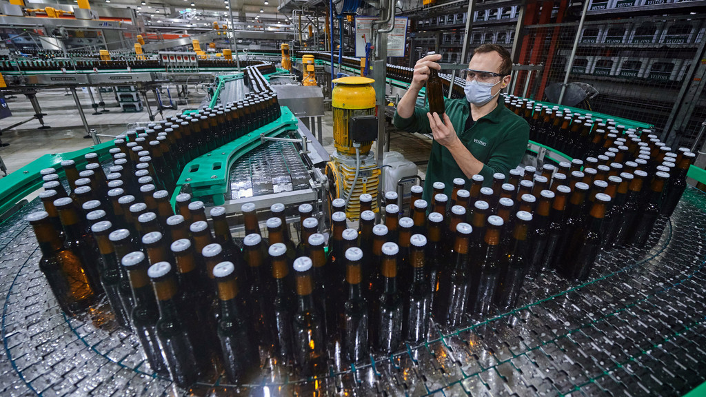 Mitarbeiter Sergej Eichler kontrolliert in der Flaschenabfüllung einer Brauerei eine Flasche. 