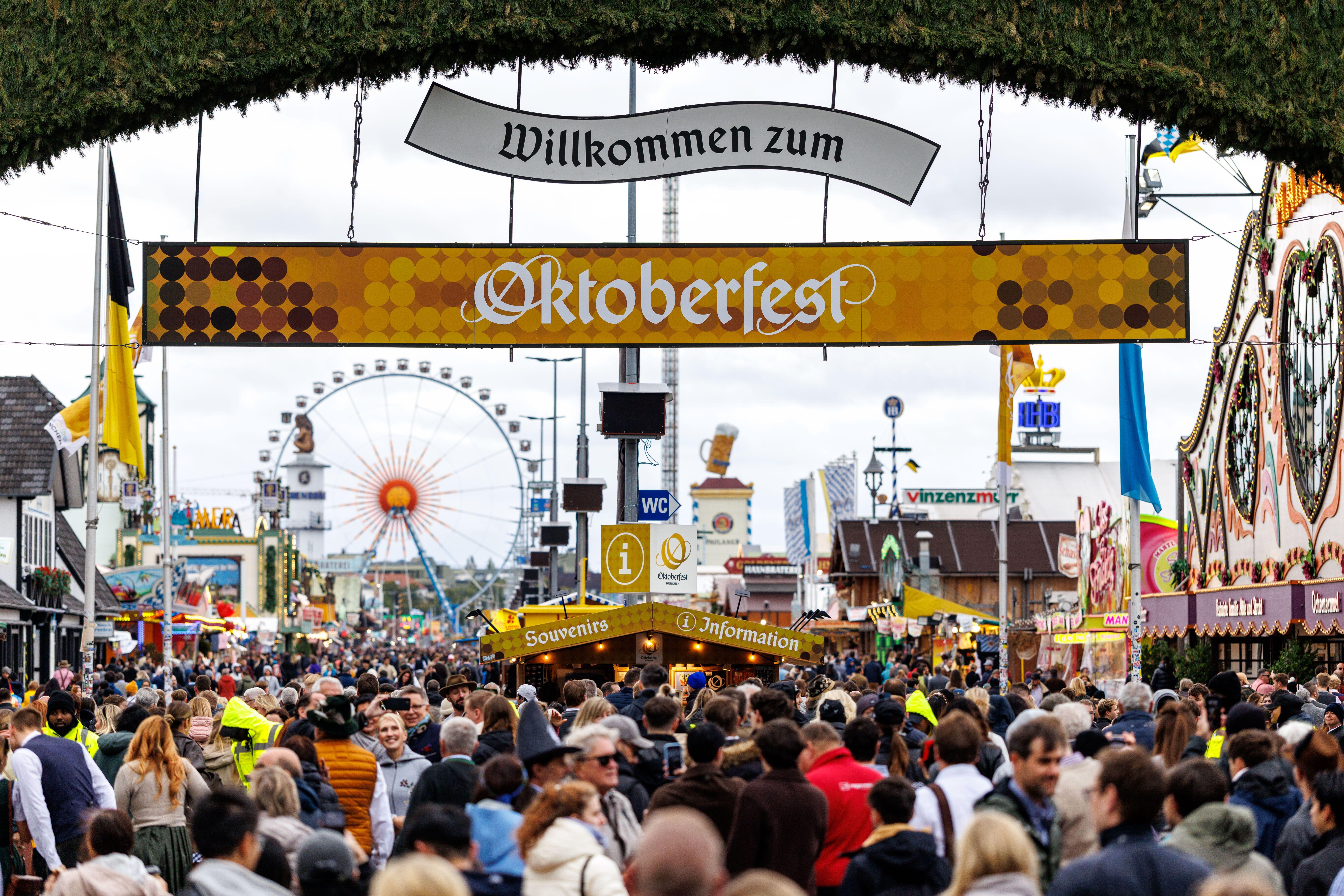ARCHIV (05.10.2025). Symbolbild eingang Oktoberfest. Zahlreiche Besucher gehen am 05.10.2025 am frühen Morgen kurz nach der ffnung durch das Tor vom Haupteingang auf das 190. Oktoberfest auf der Theresienwiese in München (Bayern, Deutschland), während im Hintergrund die Bierzelte (Festzelte) der Brauereien und das Riesenrad zu sehen sind. 