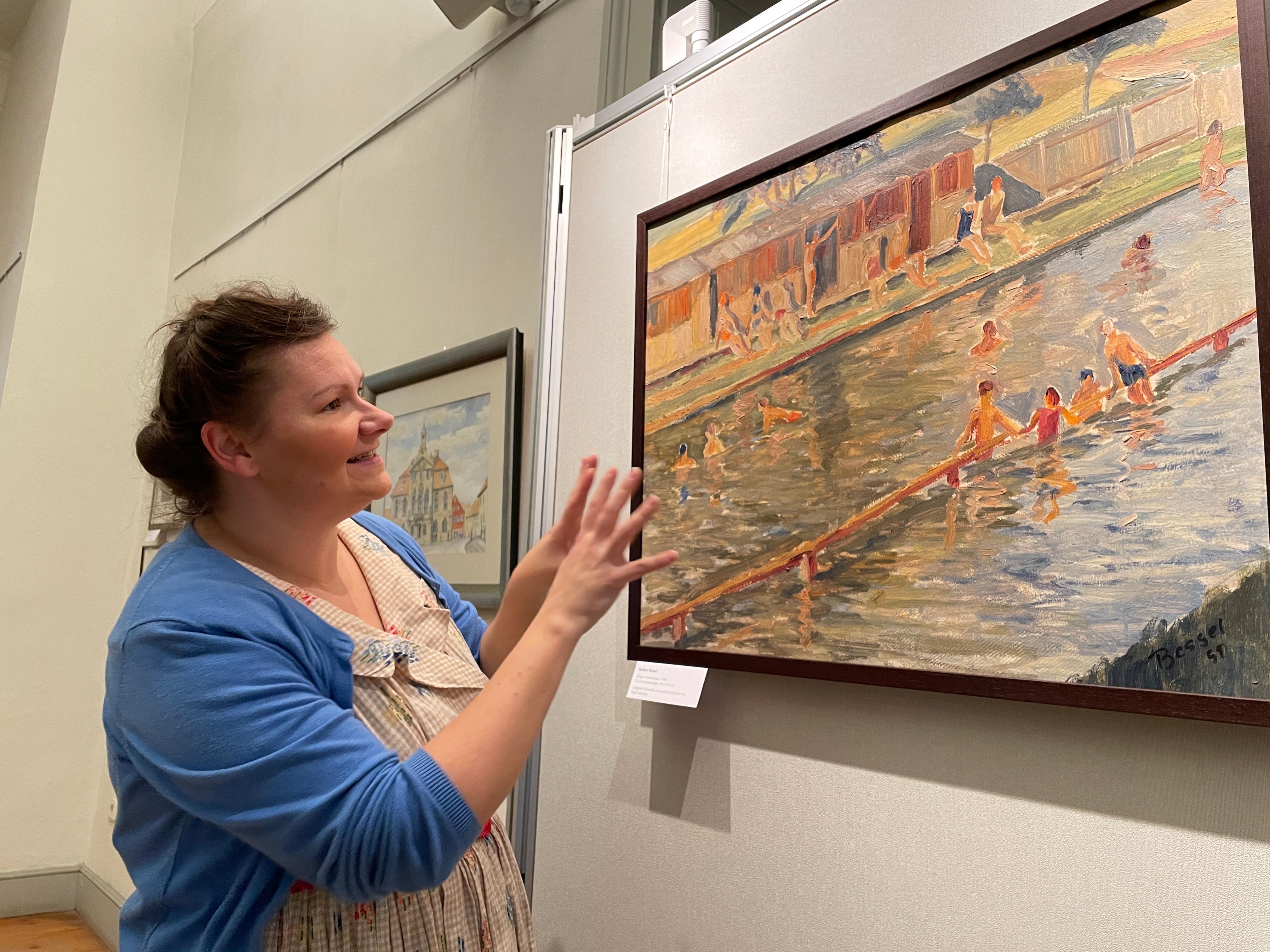 Theaterpädagogin Antje Wagner im Kostüm der 50-er Jahre zeigt ein Bild aus Ellingens Freibad vom Kunststudenten Herbert Bessel aus dem Jahr 1951 