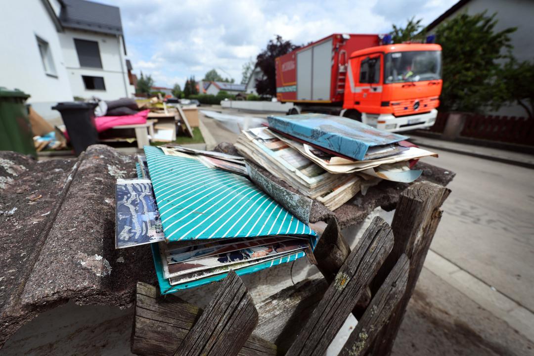 Bayern, Baar-Ebenhausen: Vom Hochwasser zerstörte Fotoalben liegen vor einem Wohnhaus.