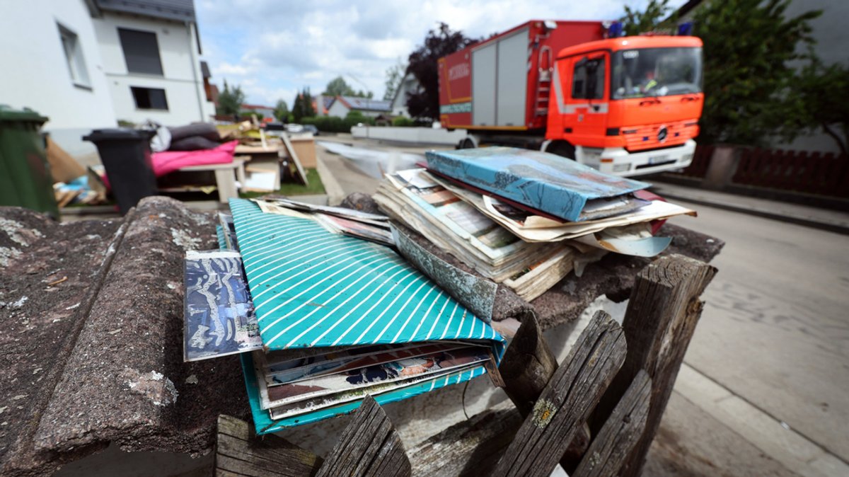 Bayern, Baar-Ebenhausen: Vom Hochwasser zerstörte Fotoalben liegen vor einem Wohnhaus.