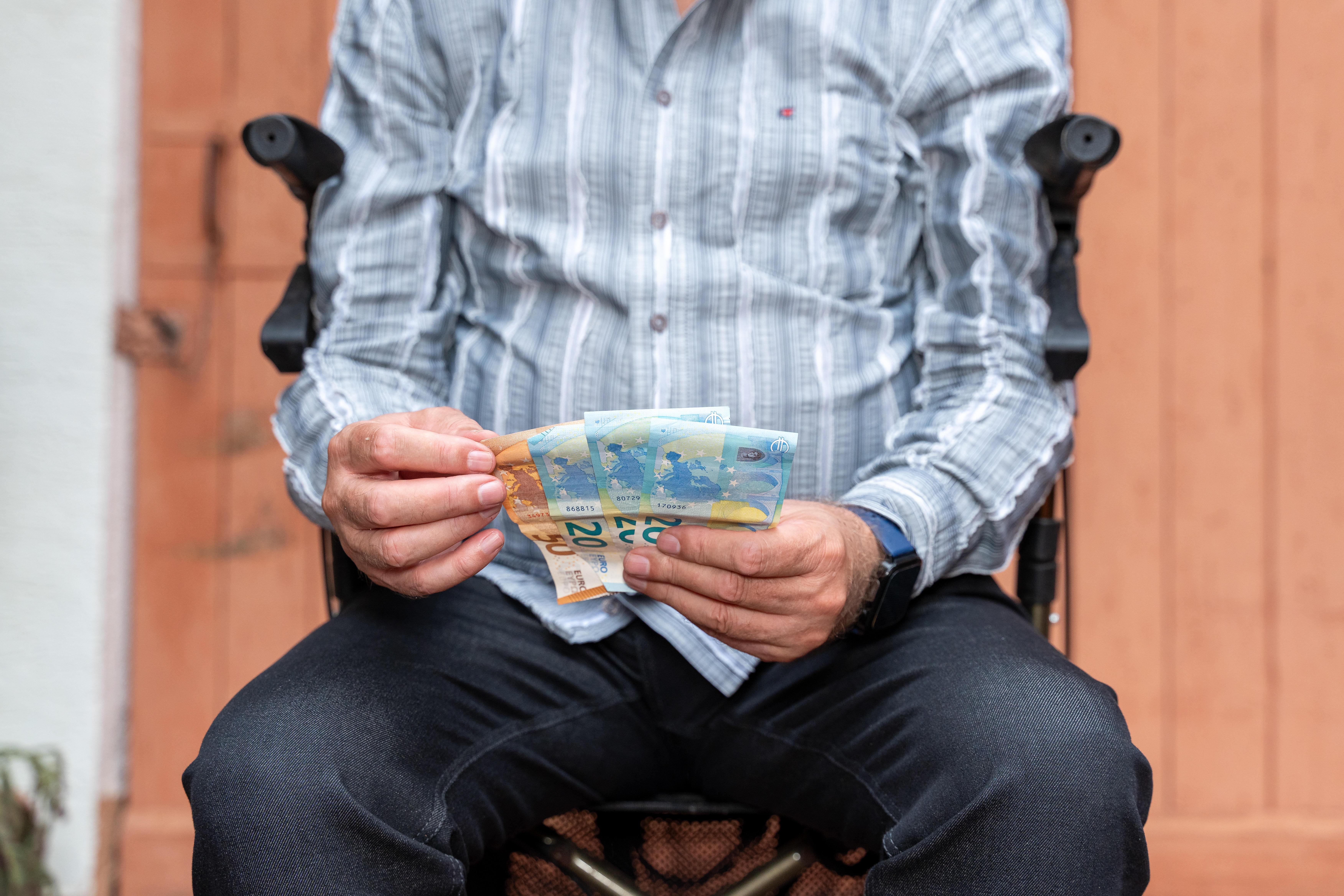 (Symbolbild) Älterer Mann mit Rolator mit Geldscheinen in der Hand.