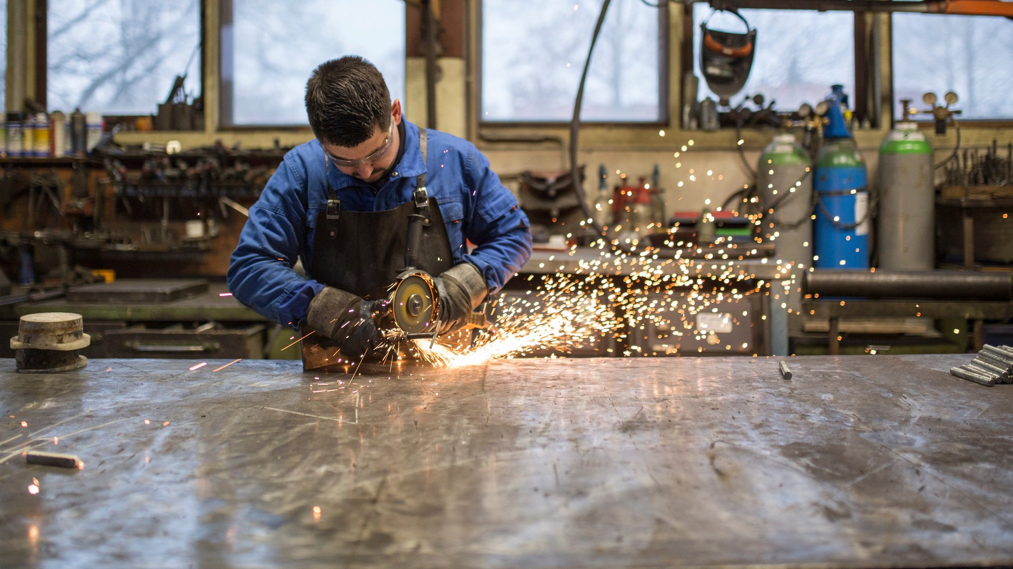 Ein Arbeiter mit einem Flex-Gerät arbeitet an einem Metallteil.