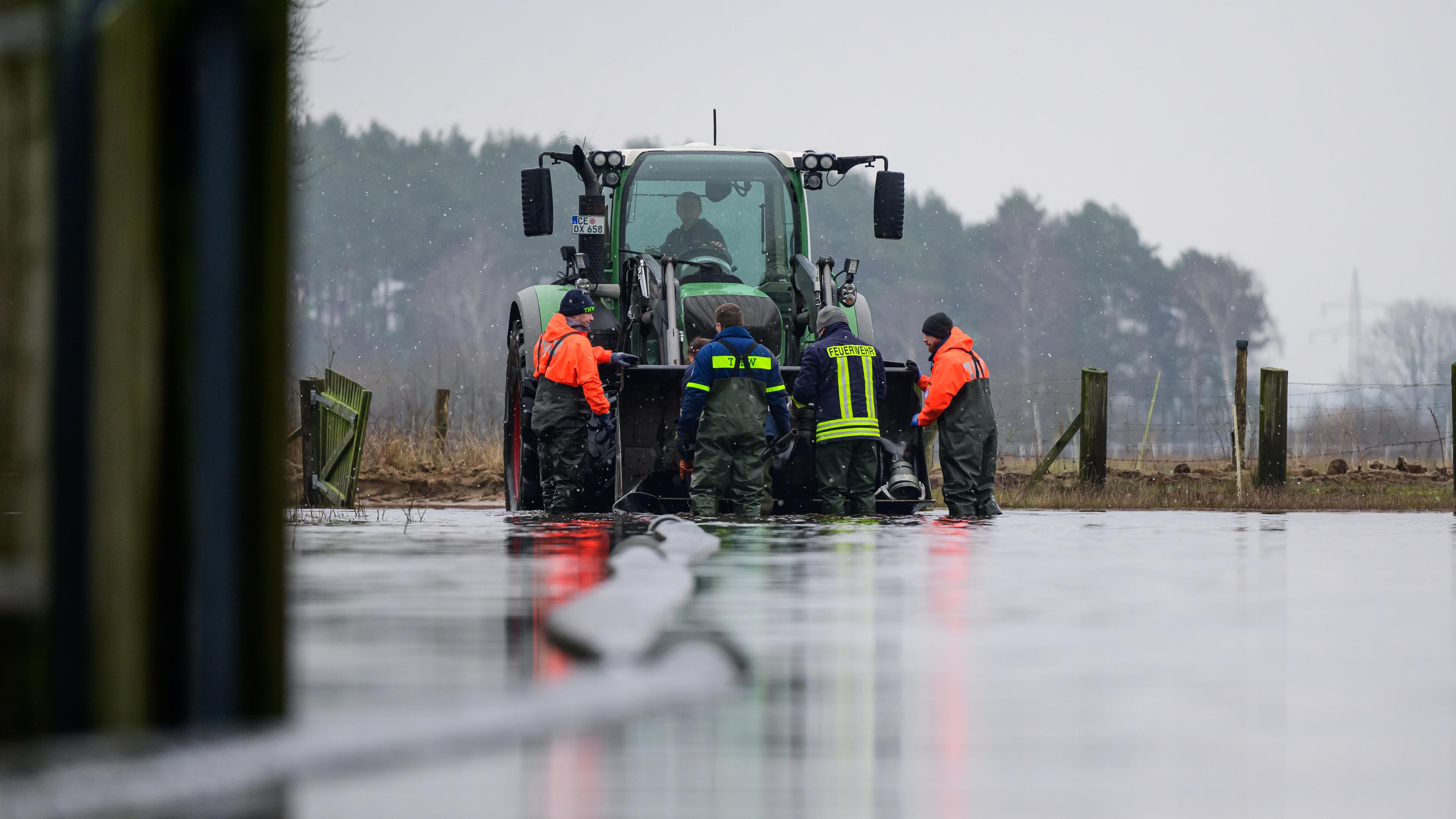 Ehrenamtliche Helfer des Technischen Hilfswerks, der Feuerwehr sowie ein Landwirt arbeiten an einer Einsatzstelle unweit der Aller.