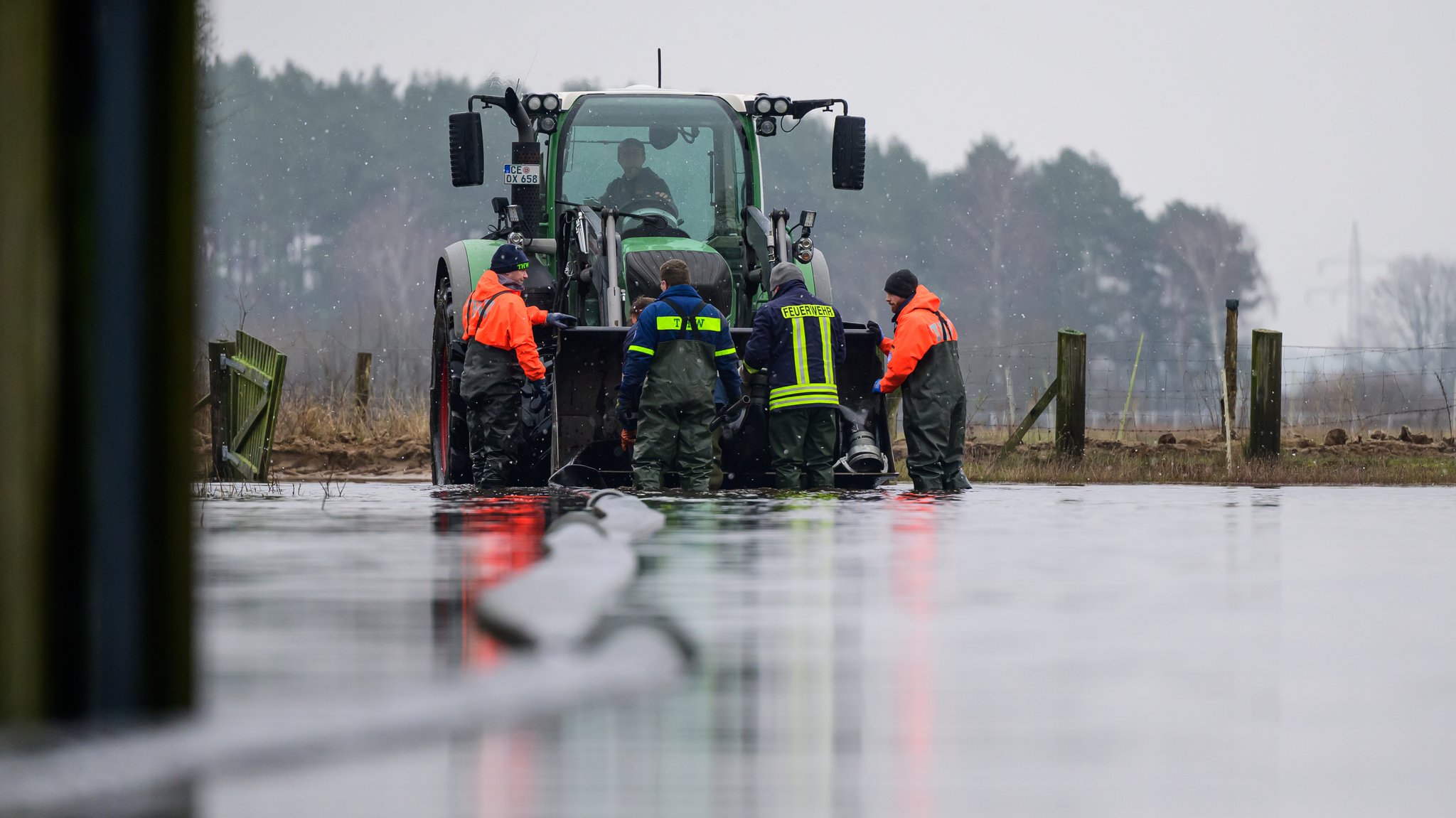 Ehrenamtliche Helfer des Technischen Hilfswerks, der Feuerwehr sowie ein Landwirt arbeiten an einer Einsatzstelle unweit der Aller.