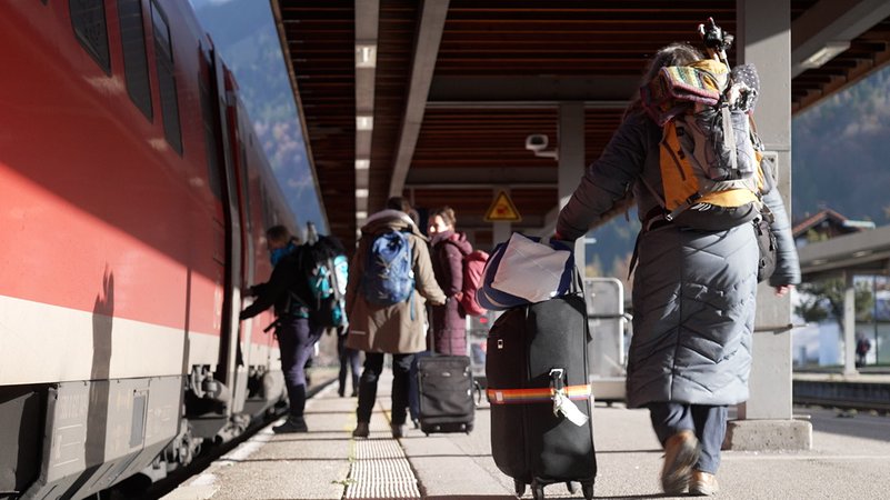 Mehrere Menschen mit Koffern und Rucksäcken steigen am Bahnhof in Oberstdorf in einen roten Regionalzug | Bild: BR/Johannes Hofmann Mehrere Menschen mit Koffern und Rucksäcken steigen am Bahnhof in Oberstdorf in einen roten Regionalzug