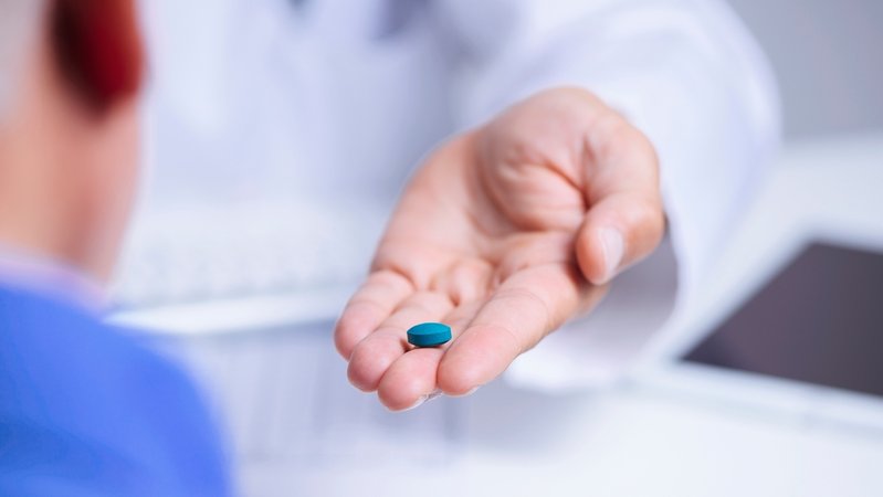 Ein Arzt reicht einem Mann eine Viagra Pille.