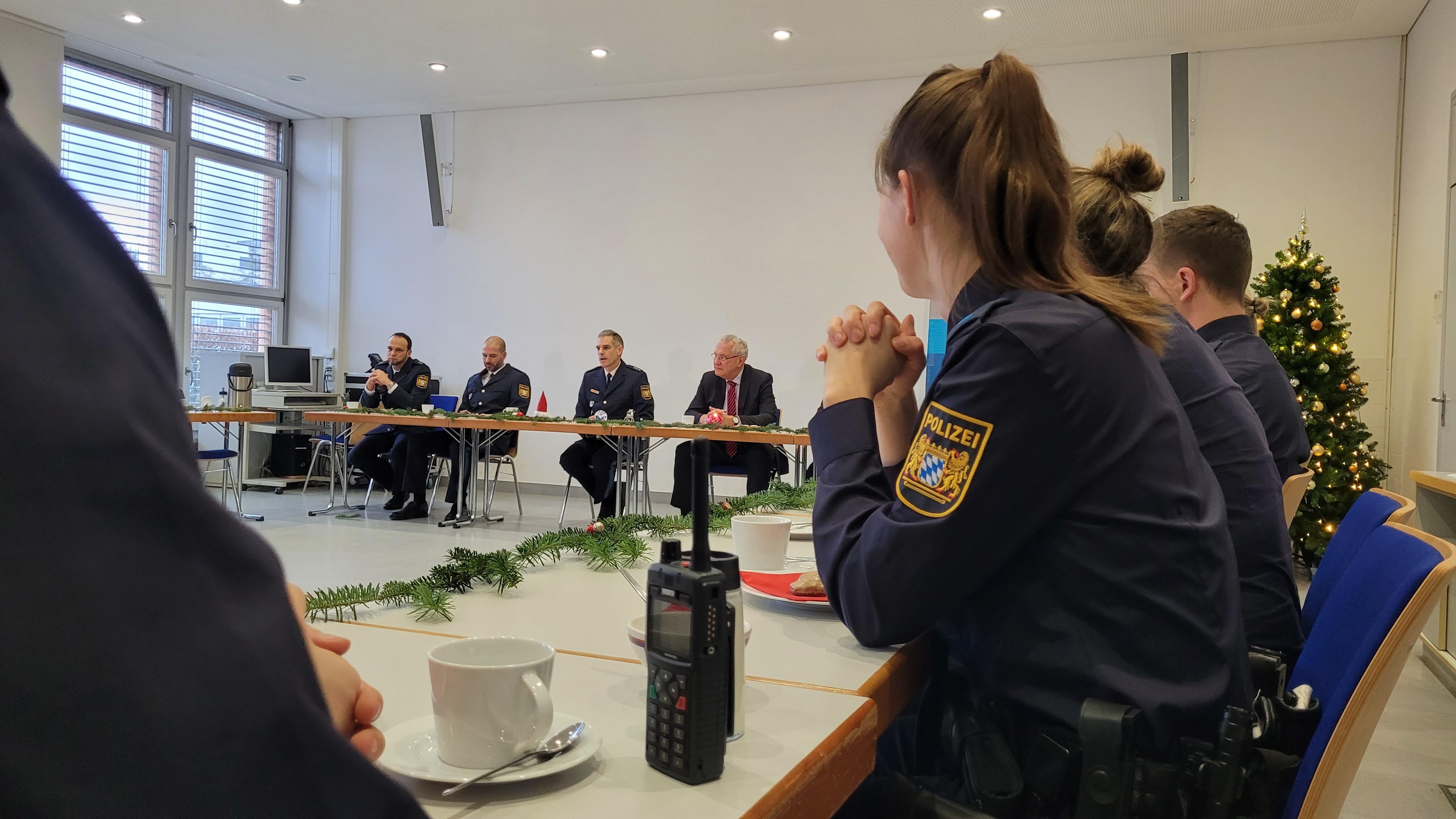 Dienststellenleiter in Erlangen, Polizeidirektor Klaus Wild (3.v.l.) und Innenminister Joachim Herrmann in einem Besprechungszimmer, im Vordergrund Polizistinnen und Polizisten in Uniform