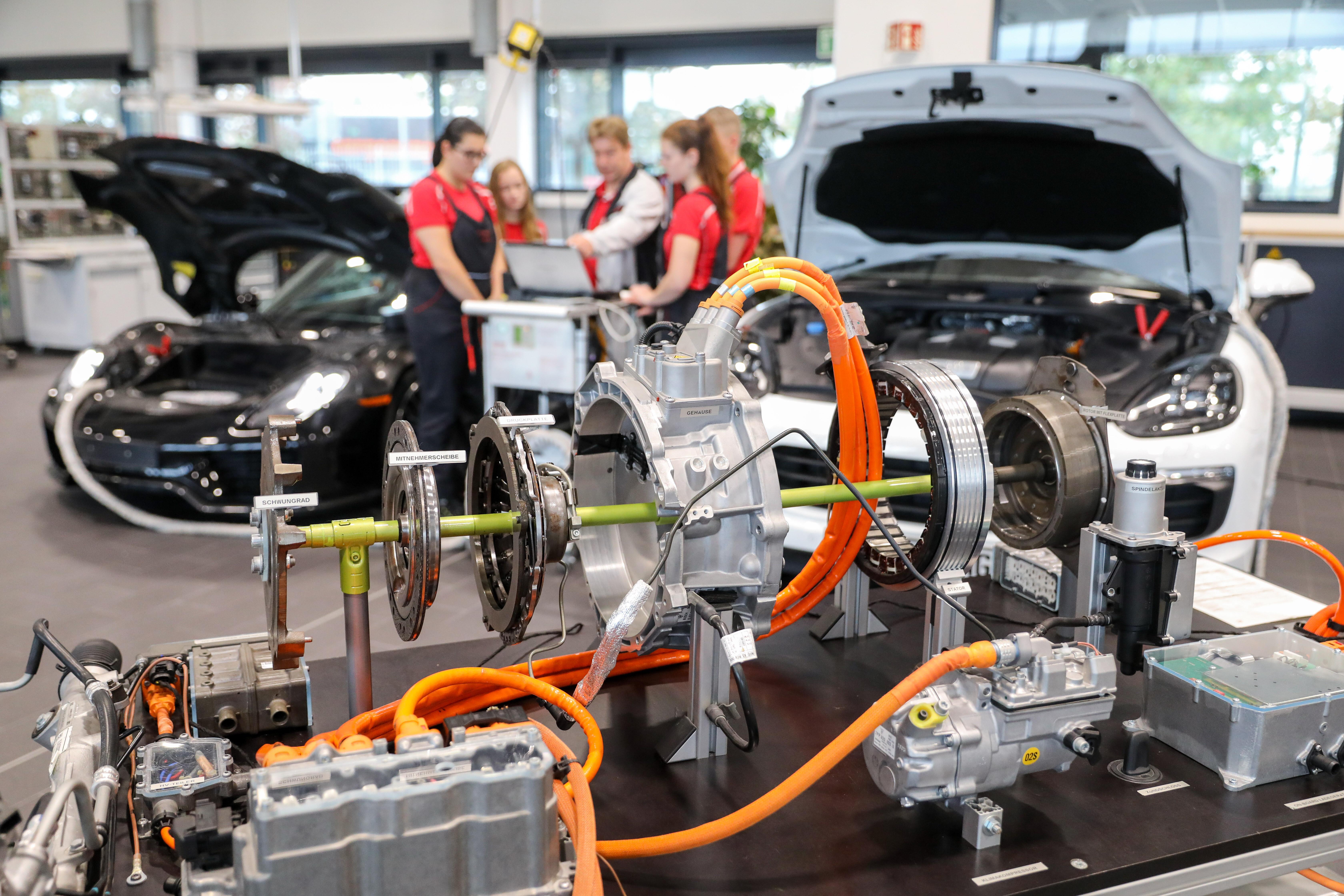 Ausbilder erläutert Auszubildenden im 2. Lehrjahr die Funktionsweise eines Hybridantriebes an einem Modellaufbau im Porsche Ausbildungszentrum. 