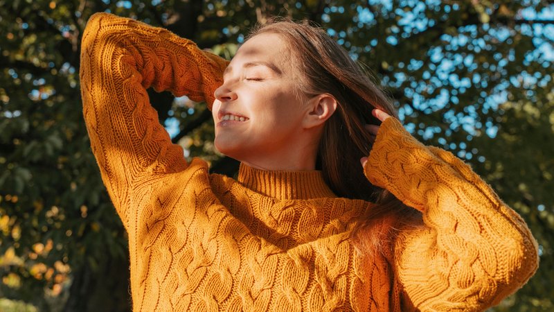 Eine Frau im orangen Pullover schaut genießerisch in die Herbstsonne | Bild: picture alliance / Westend61 | Ok Shu Eine Frau im orangen Pullover schaut genießerisch in die Herbstsonne