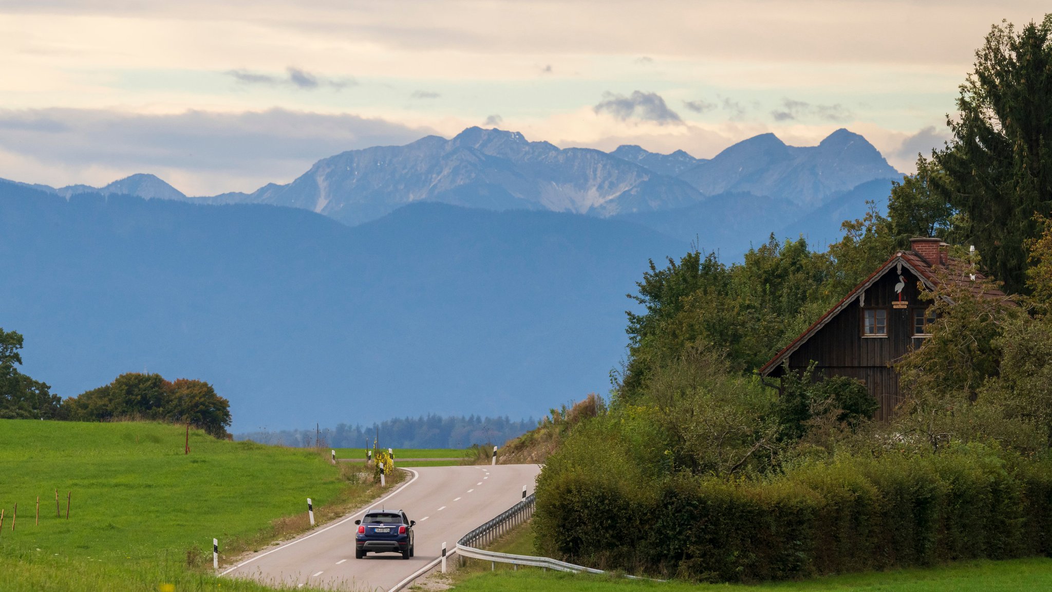 Ein PKW fährt bei Münsing über eine Landstraße nahe dem Starnberger See in Richtung Süden den Bergen entgegen (Symbol- und Archivbild)