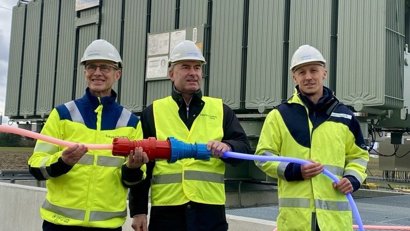 Bayerns Wirtschaftsminister Hubert Aiwanger nahm die neue Einspeisesteckdose mit Egon Westphal, dem Vorstandsvorsitzenden der Bayernwerk AG und Thilo Hoffmann, dem Leiter Planung/Bau Umspannwerke & Schaltstationen bei Bayernwerk AG, in Niederviehbach in Betrieb. | Bild: BR/ Harald Mitterer Bayerns Wirtschaftsminister Hubert Aiwanger nahm die neue Einspeisesteckdose mit Egon Westphal, dem Vorstandsvorsitzenden der Bayernwerk AG und Thilo Hoffmann, dem Leiter Planung/Bau Umspannwerke & Schaltstationen bei Bayernwerk AG, in Niederviehbach in Betrieb.