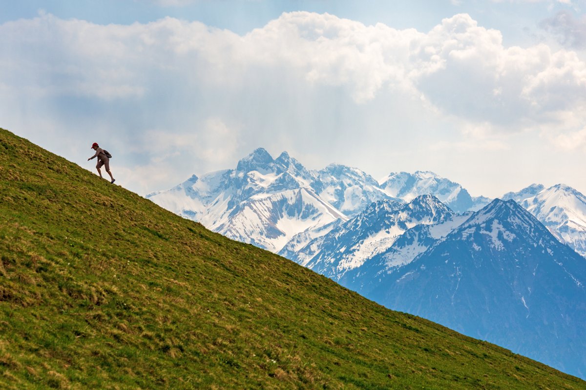 Ein einsamer Wanderer läuft in den Allgäuer Alpen den Berg rauf.