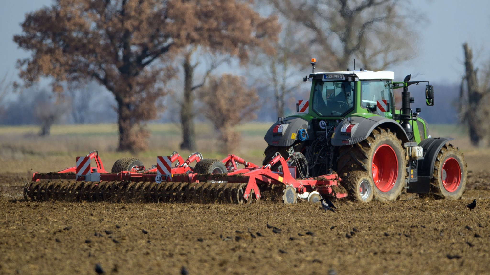 Ein Landwirt fährt mit seinem Traktor und angehängter Egge über ein Feld.