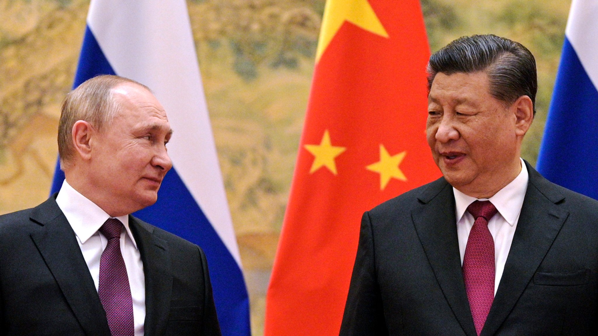 ARCHIV - 04.02.2022, China, Peking: Wladimir Putin (l), Präsident von Russland spricht mit Xi Jinping, Präsident von China, während ihres Treffens in Peking. Der per Haftbefehl des Weltstrafgerichts zur Fahndung ausgeschriebene Kremlchef Putin empfängt in Moskau Chinas Staatschef Xi Jinping als Freund in Kriegszeiten.