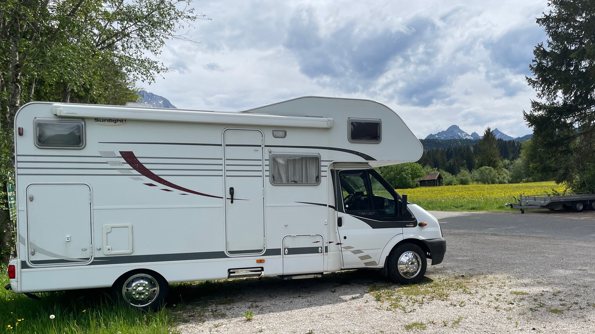 Wohnmobil auf einem Parkplatz vor Bergpanorama.