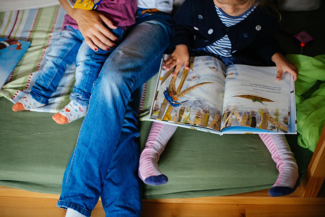Eine Mutter liest ihren Kindern aus einem Bilderbuch vor.