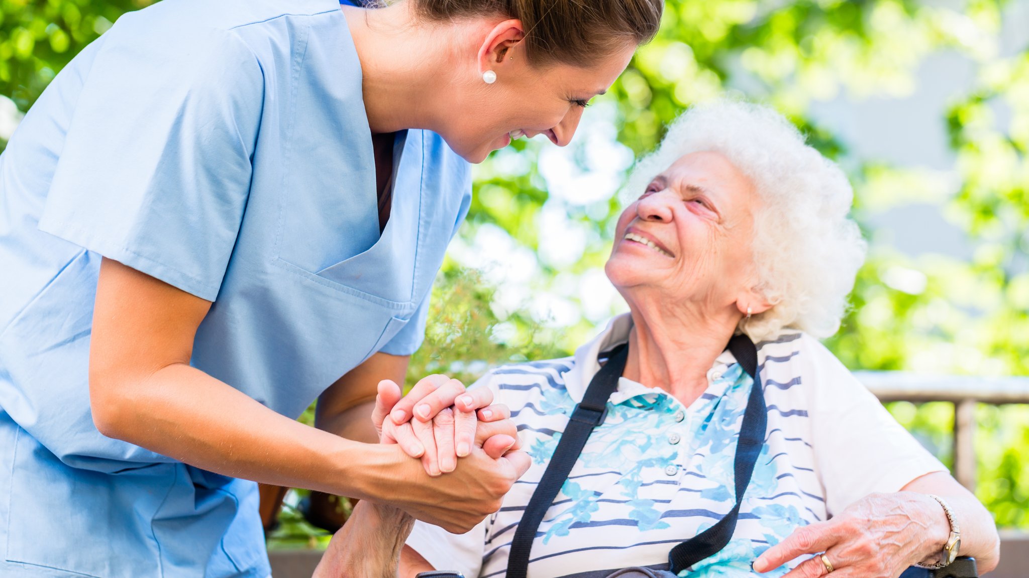 Pflegerin hält Hand einer Seniorin