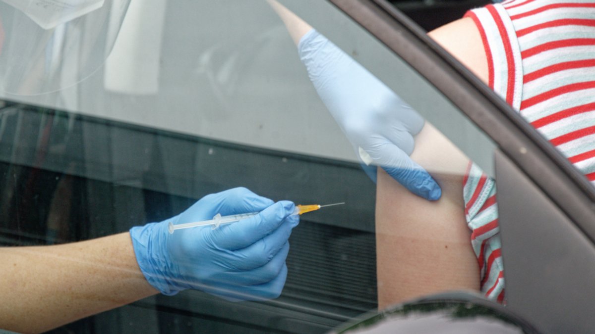 Spritze zum Impfen wird im Auto angesetzt.