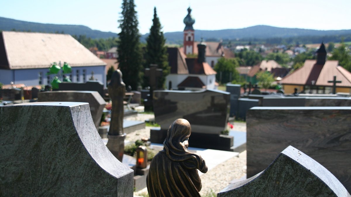 Blick zwischen zwei Gräbern auf dem Friedhof in Eslarn auf die Dorfkirche