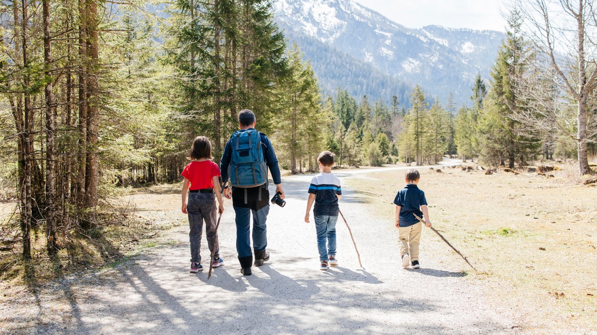 Eine Familie beim gemeinsamen Wandern vor Bergkulisse.
