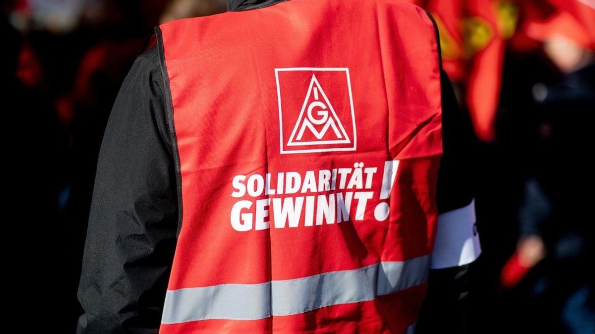 Ein Teilnehmer einer Kundgebung der IG Metall trägt eine rote Weste mit der Aufschrift "Solidarität gewinnt!"