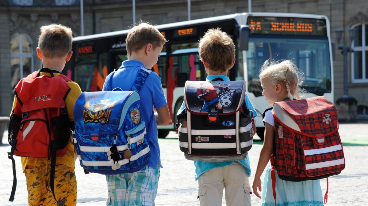 Kinder gehen auf einen Schulbus zu (Symbolbild).