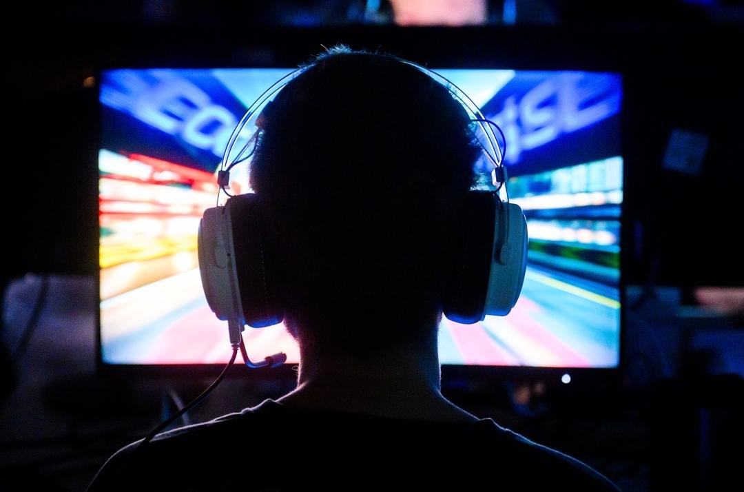 (Symbolbild) Eine Person sitzt mit Headset vor einem Bildschirm. 