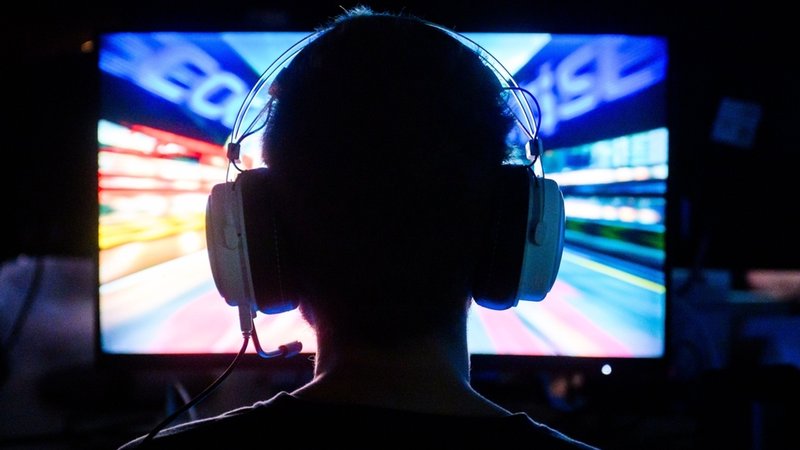(Symbolbild) Eine Person sitzt mit Headset vor einem Bildschirm. | Bild: dpa-Bildfunk/Julian Stratenschulte (Symbolbild) Eine Person sitzt mit Headset vor einem Bildschirm.