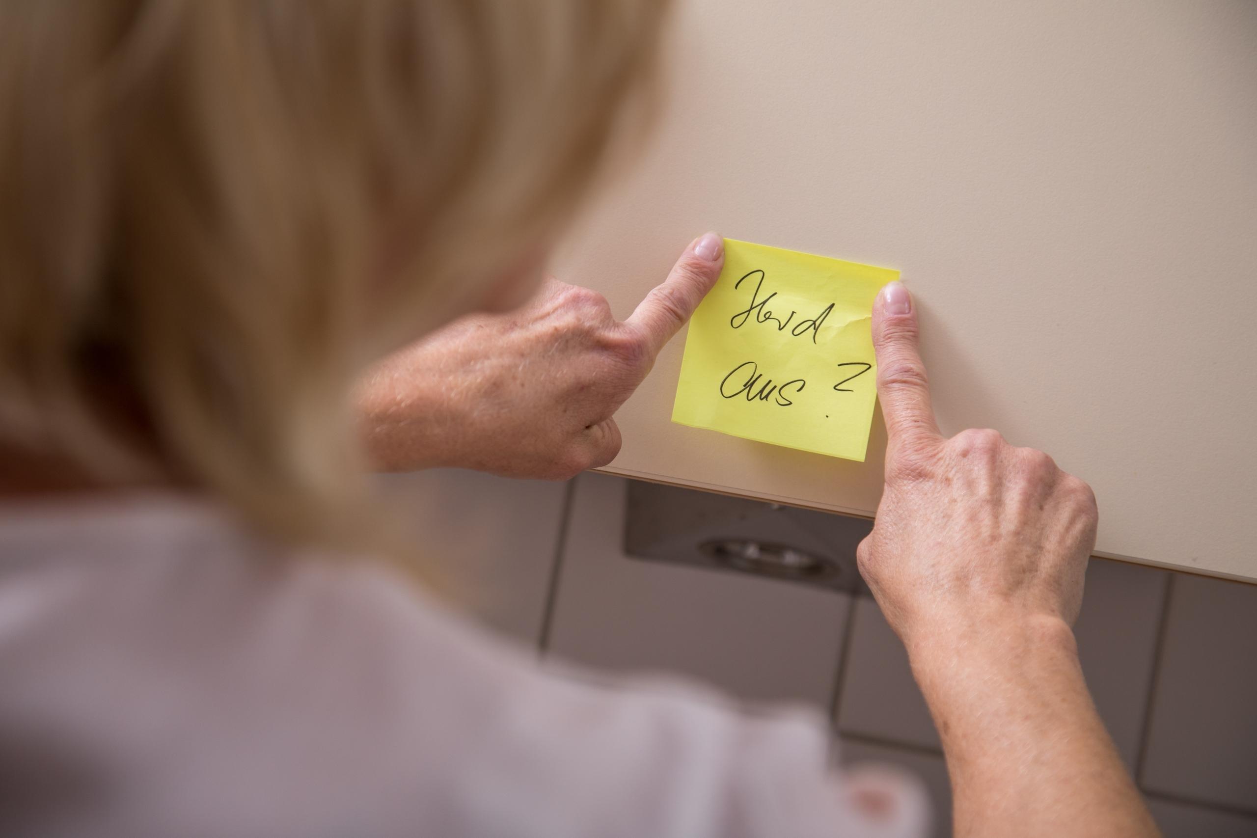 Eine Frau klebt einen Zettel zur Erinnerung in die Küche