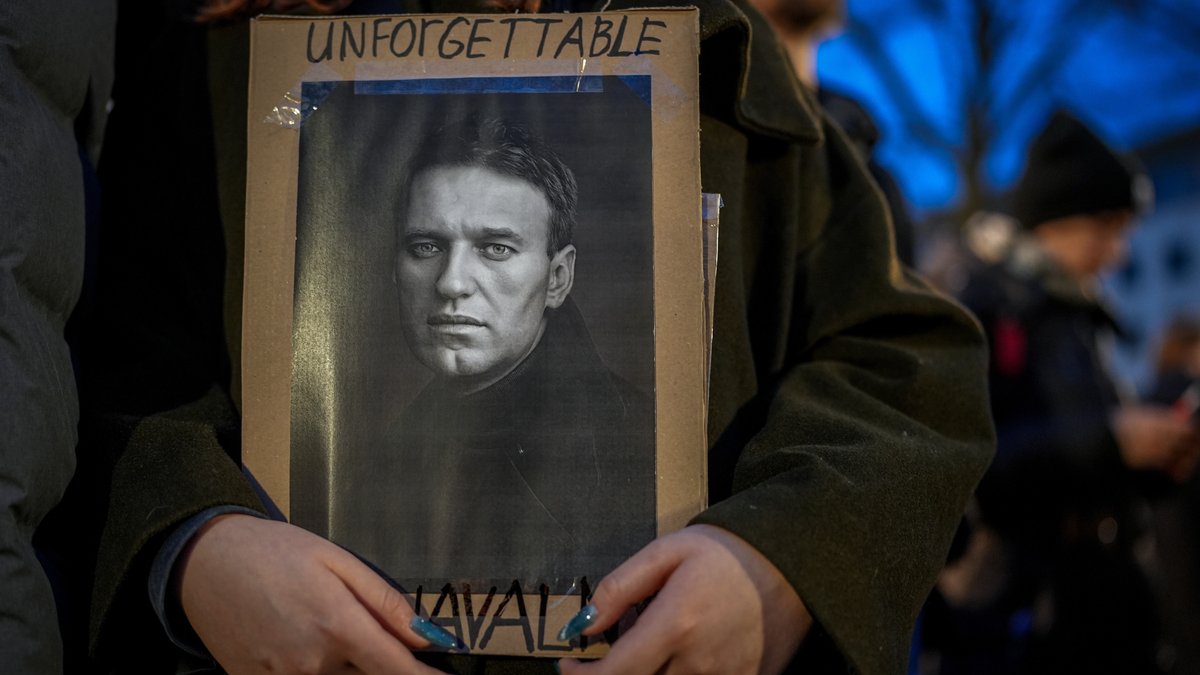 Eine Frau hält ein Bild von Alexej Nawalny mit der Aufschrift "unforgettable" (unvergesslich)