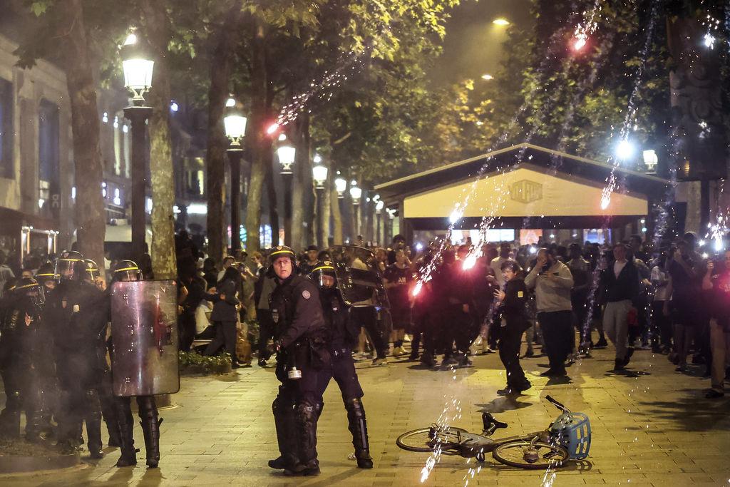 01.06.2025, Frankreich, Paris: Polizeikräfte beobachten, wie nach dem Champions-League-Finale zwischen Paris Saint-Germain und Inter Mailand am Elysee-Palast in Paris Fackeln auf ihre Position fallen. Foto: Thomas Padilla/AP/dpa +++ dpa-Bildfunk +++