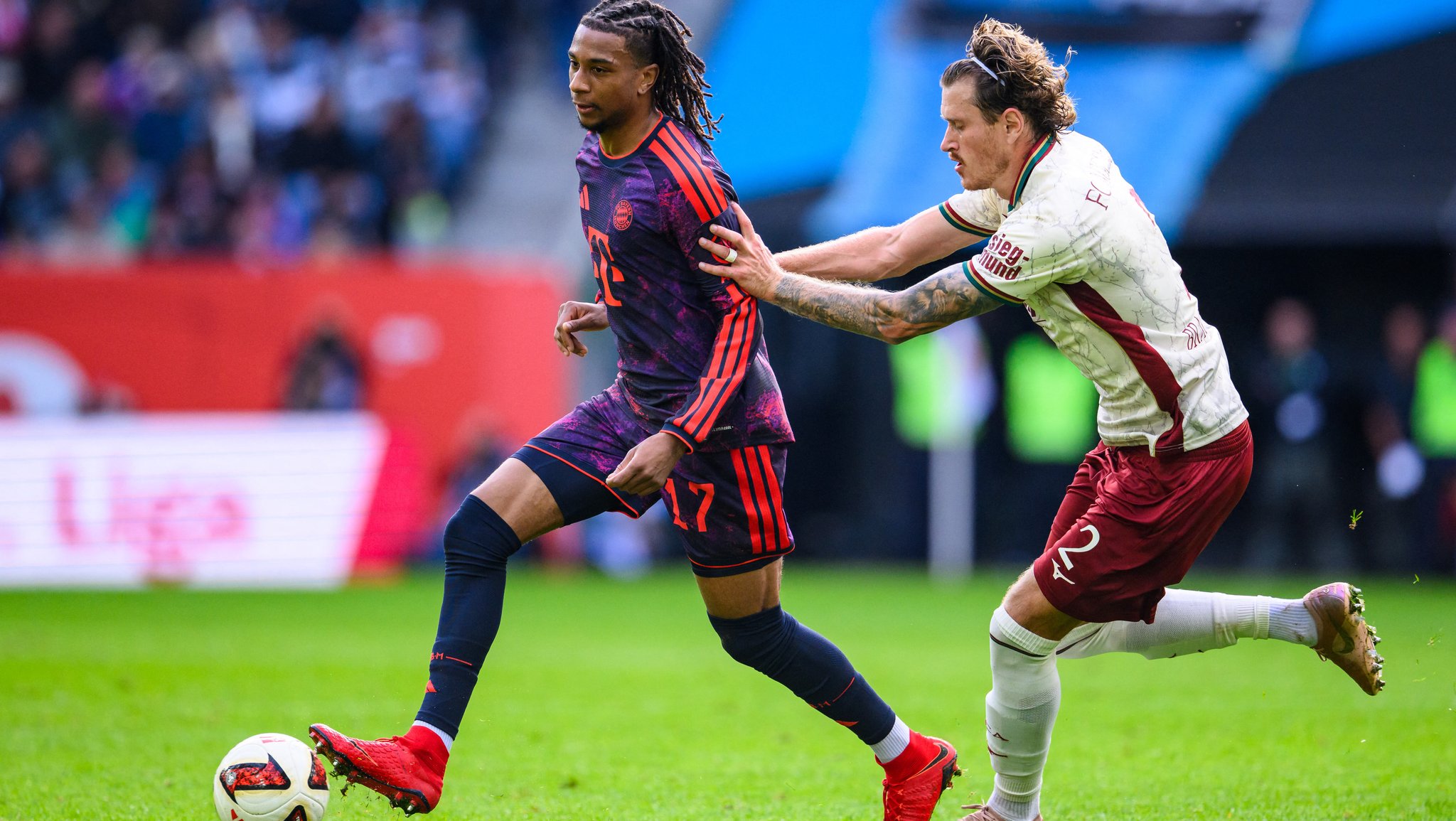 Michael Olise und Calvin Brackelmann im Zweikampf | Bild: fc-augsburg-fc-bayern-muenchen-highlights-bundesliga-5-spieltag-saison-202627-100 Michael Olise und Calvin Brackelmann im Zweikampf