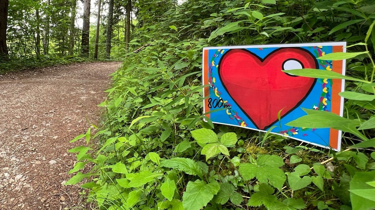 Neben einem Wanderweg steht ein Schild mit einem roten Herz als Symbol für die kardiovaskuläre Teststrecke.