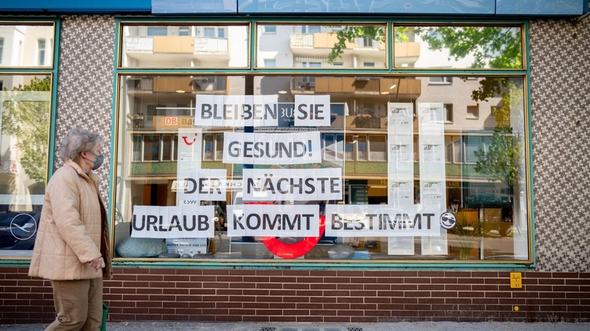 Eine Passantin geht am Schaufenster eines Reisebüros vorbei.