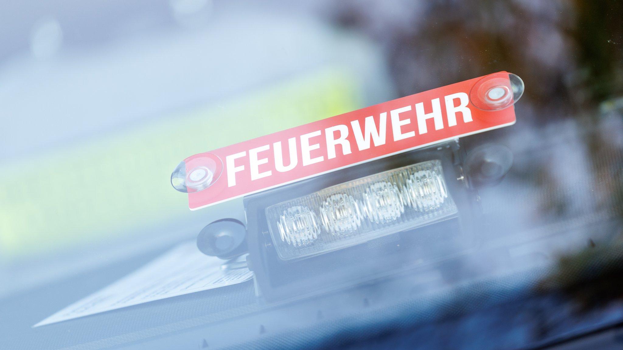 Schriftzug "Feuerwehr" und ein Blaulicht in der Windschutzscheibe eines Einsatzfahrzeugs (Symbolbild)