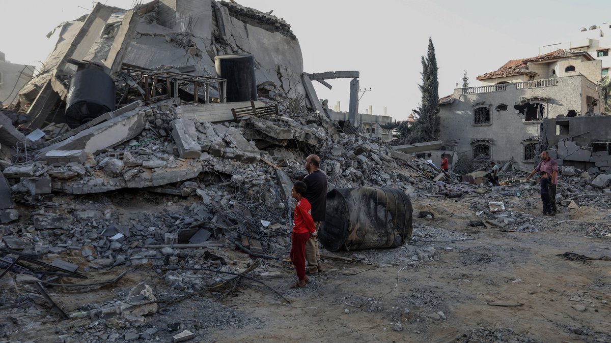 Menschen vor einem durch Bomben zerstörten Haus in Rafah