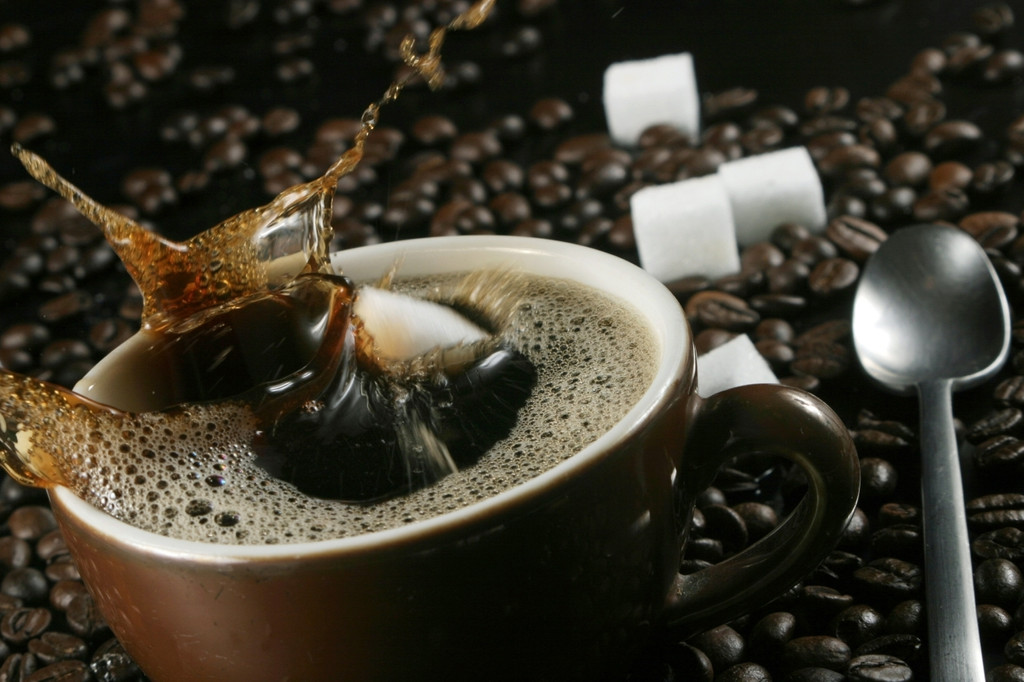 Tasse Kaffee, Kaffeebohnen und Zuckerwürfel