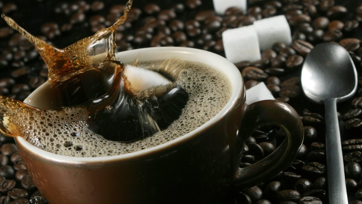 Tasse Kaffee, Kaffeebohnen und Zuckerwürfel