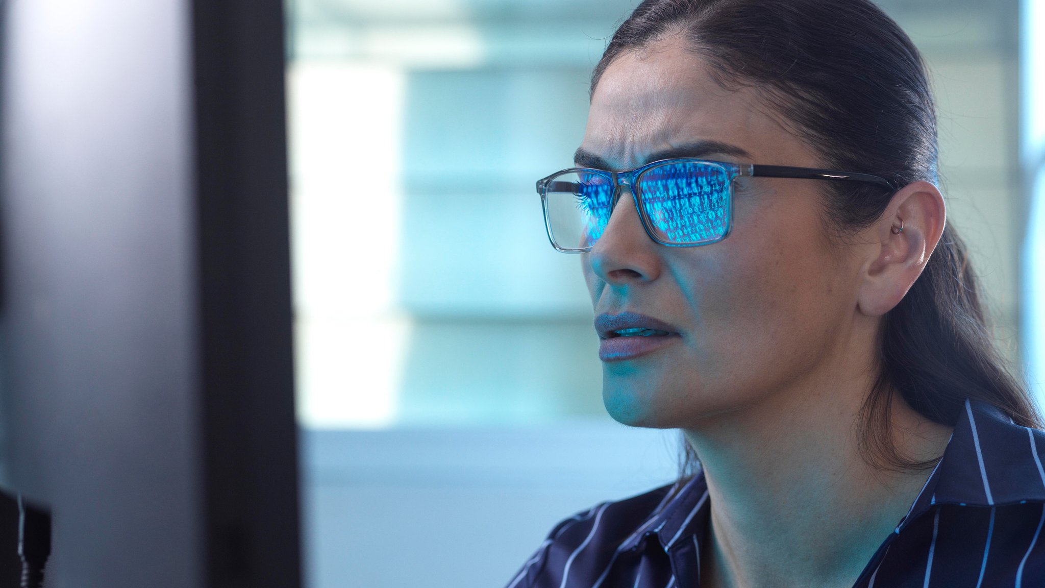 Ein Bildschirm spiegelt sich in der Brille einer Frau.