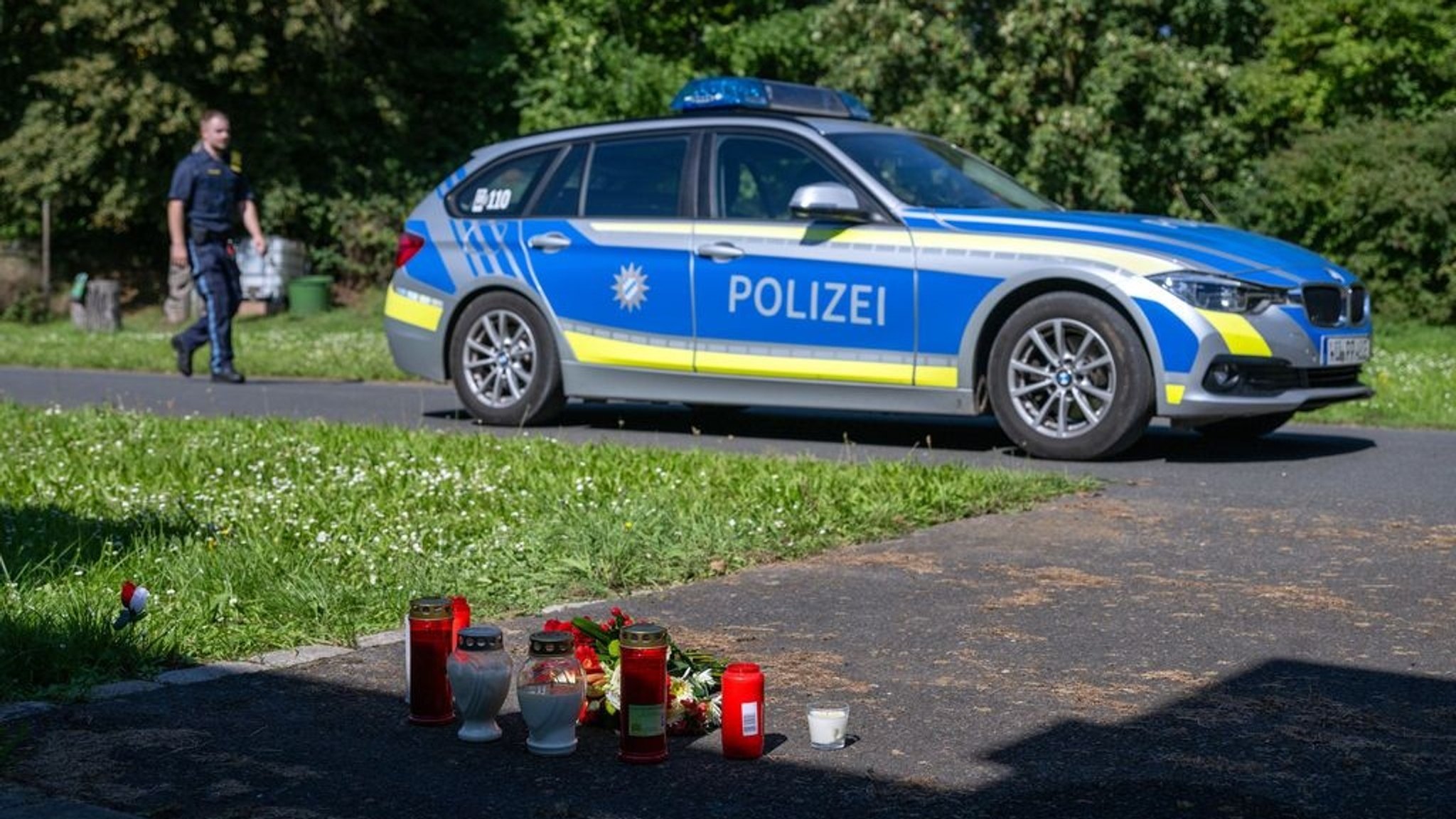 ARCHIV - 09.09.2023, Bayern, Lohr Am Main: Kerzen und Blumen sind vor einem Seiteneingang des Schulzentrums in Lohr am Main abgelegt, dahinter steht ein Polizeiwagen. (zu dpa: «Welche bedeutenden Verfahren 2024 an Bayerns Gerichten anstehen») Foto: Pia Bayer/dpa +++ dpa-Bildfunk +++