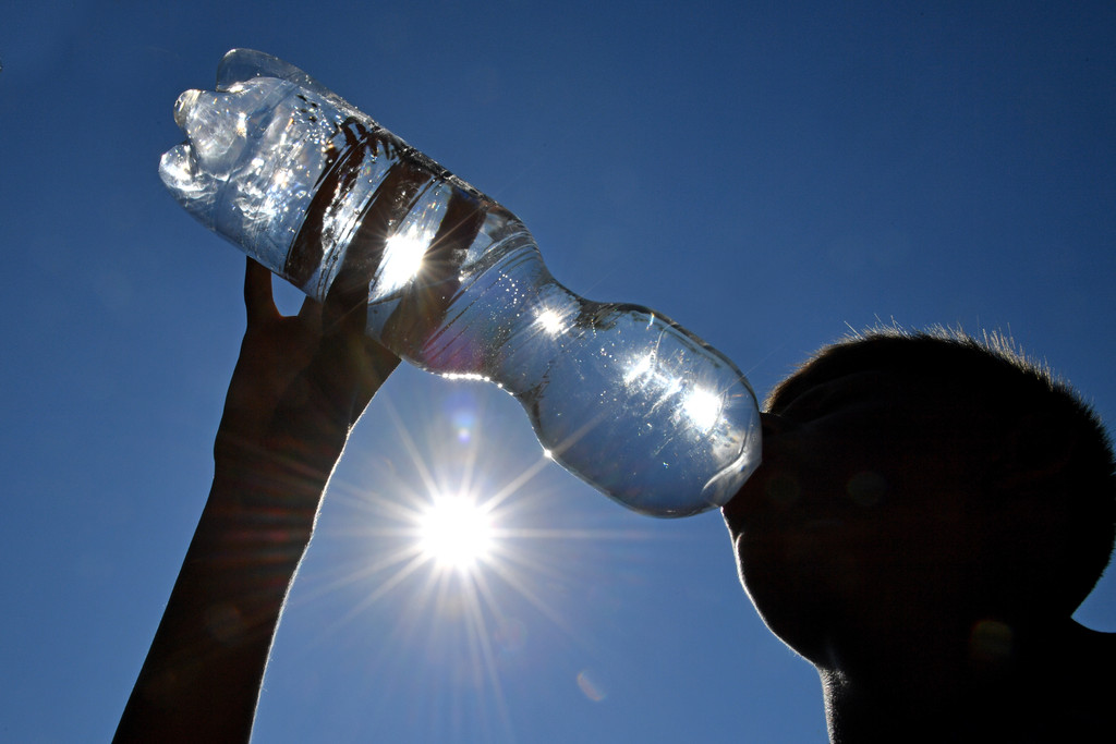 Junge trinkt aus Wasserflasche bei sehr großer Hitze (Symbolbild)