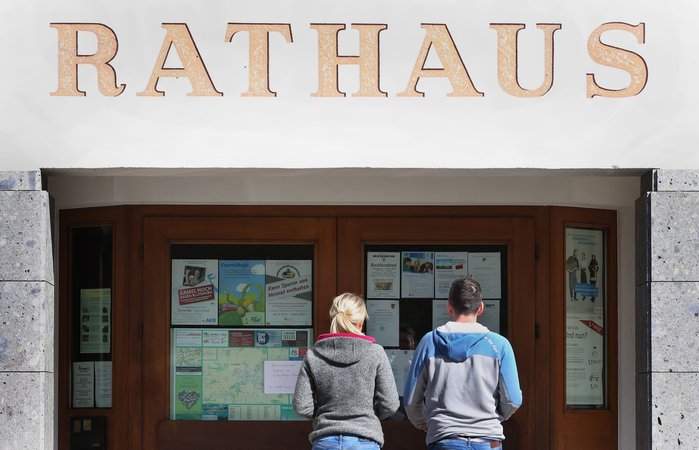Eine Frau und ein Mann betreten das Rathaus, um bei der Kommunalwahl ihre Stimmen abzugeben. (zu dpa: «Ehrenamt oder Hauptamt? Bürgermeister in kleinen Gemeinden») Foto: Karl-Josef Hildenbrand/dpa +++ dpa-Bildfunk +++