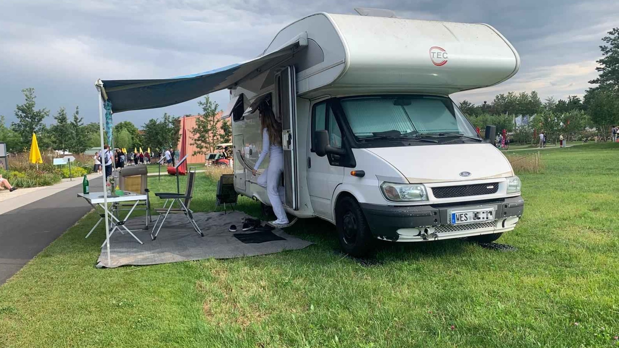 Ein Campingauto mit Tisch und Stühlen unter einem Vordach steht auf einem Rasen auf dem Gelände der Landesgartenschau bei München.